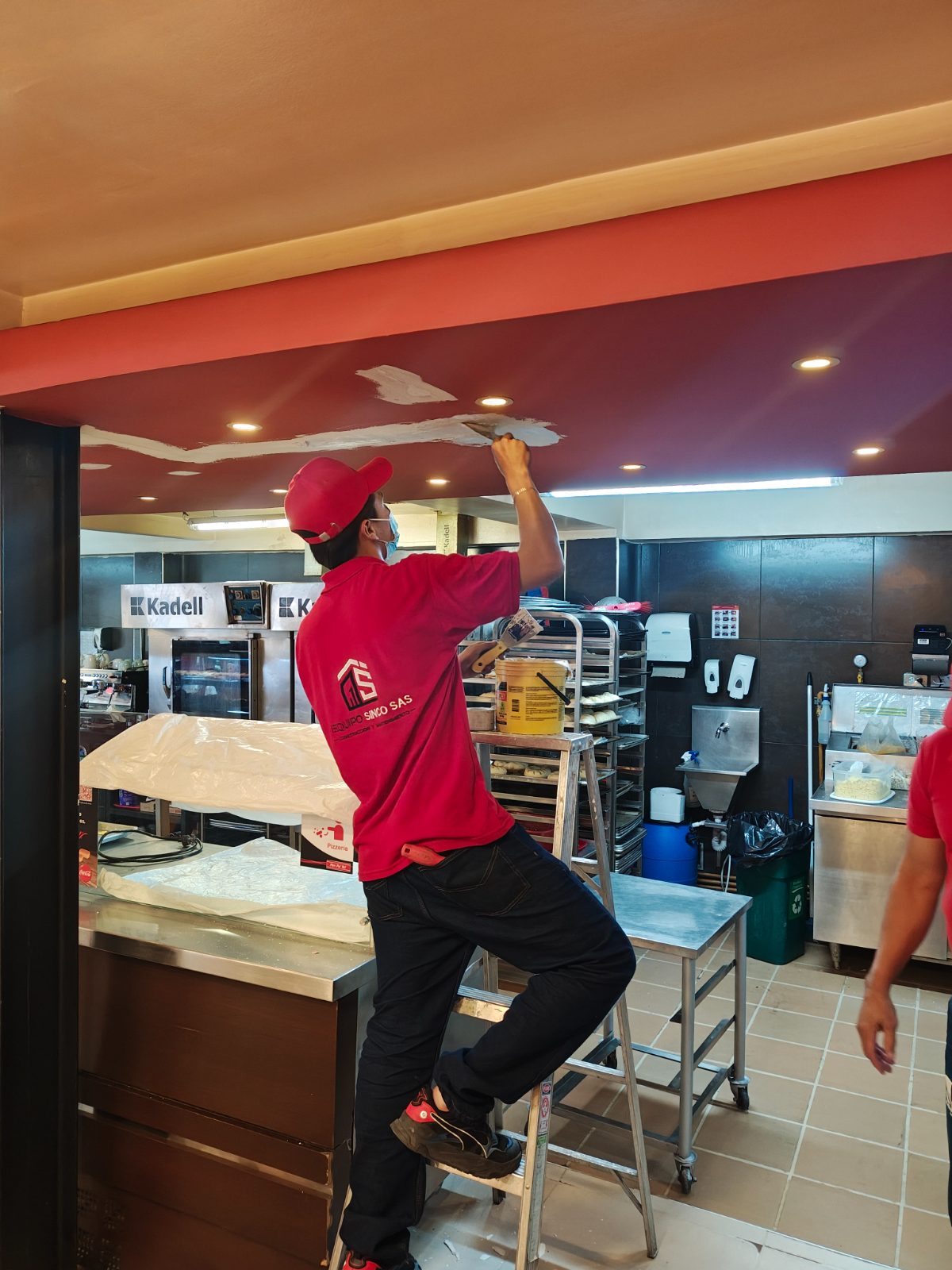 Técnico de Equipo Sinco pintando techo en local comercial